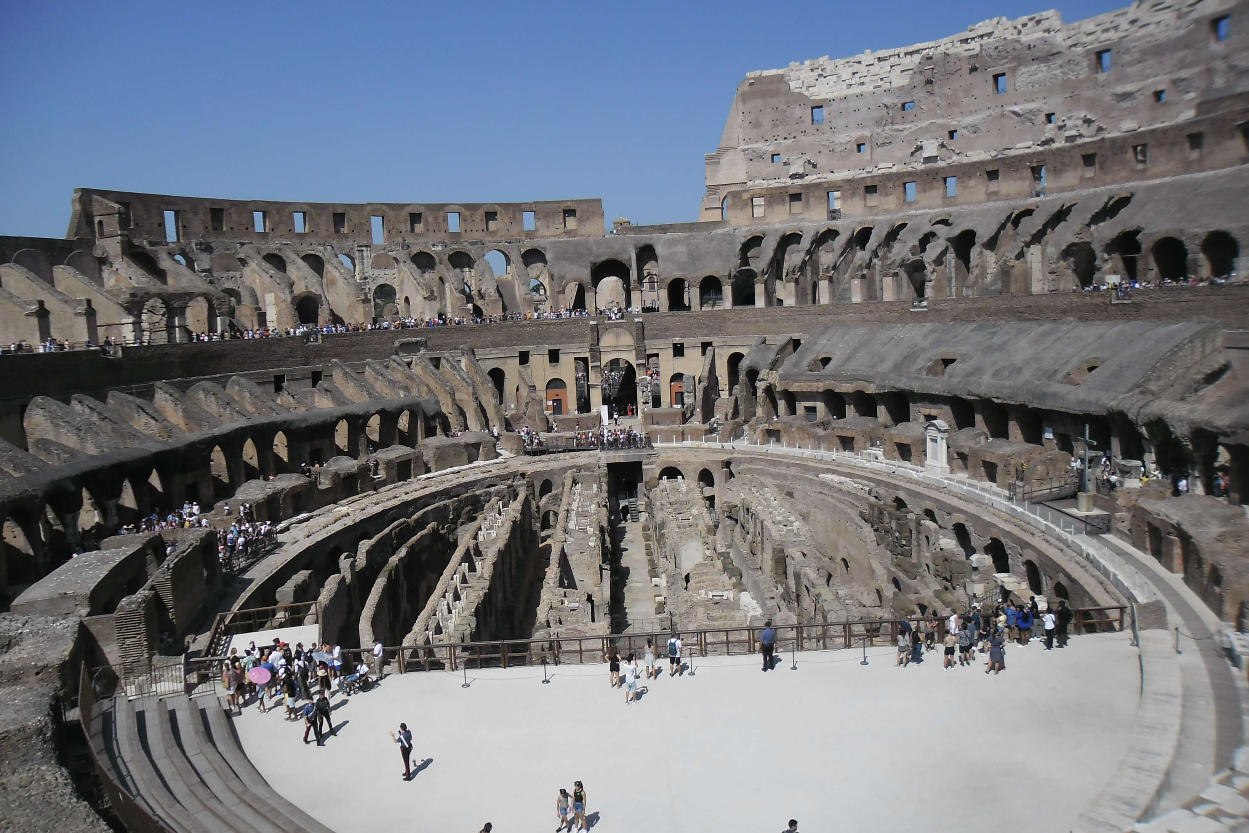 Overview of the inside of the Rome Colosseum, looking down on the underground area and dungeons, with many tourists.